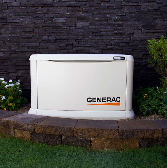 Generac Guardian whole home standby generator installed beside a stone wall, set up by trusted Generac installer, Great Lakes Electric