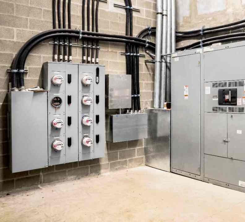 A neatly organized commercial electrical room with utility meters, conduit runs, and a large disconnect, installed by Great Lakes Electric.